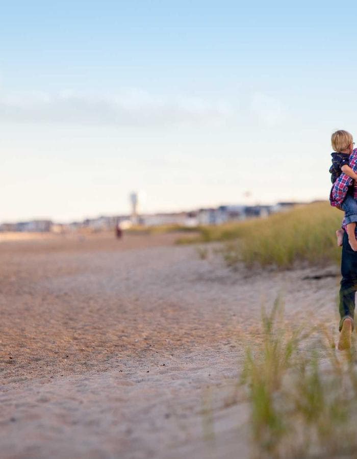 Parent holding a child while walking on the beach