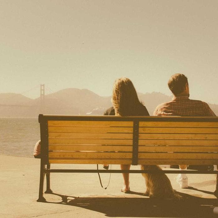 Couple sitting together on a bench at sunset